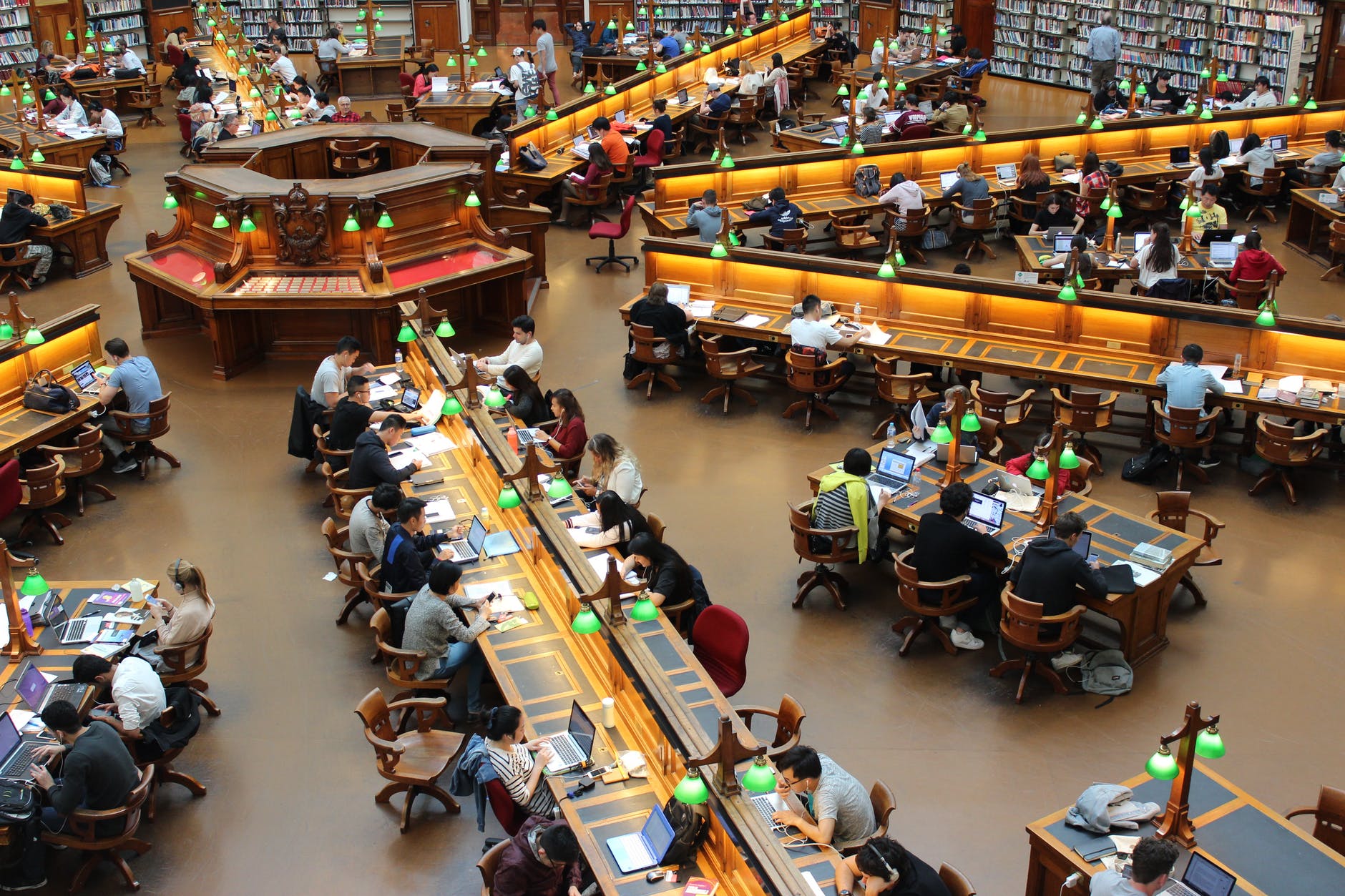 Una biblioteca enorme con varios estudiantes consultando o leyendo libros  